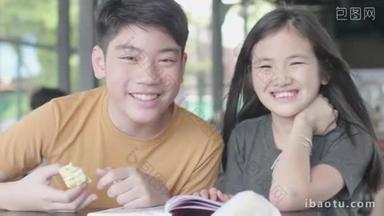 亚洲男孩和女孩<strong>放松</strong>与卡通书，可爱的亚洲孩子坐在享受阅读书在咖啡馆与笑脸. 